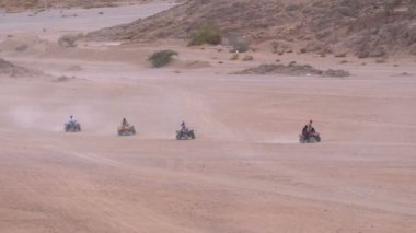 Dağların arka planında Mısır'da Çöl üzerinden Quad Bike Rides Grubu. Sürüş Avs.