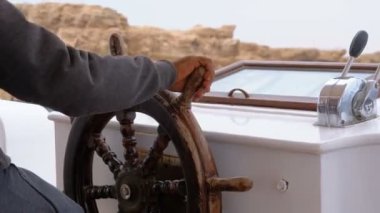 Bir zevk teknesinin direksiyonunda kaptan. Kaptan deniz yatı kontrol eder