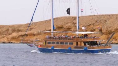 Turistler ile Güzel Ahşap Yat Kayalar arka planda Fırtınalı Denizi'nde Yelken olduğunu. Mısır