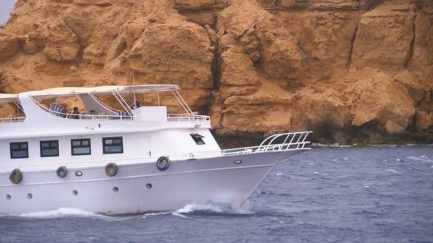 Pleasure Boat with Tourists is Sailing in the Storm Sea on background of Rocks (em inglês). Egipto — Vídeo de Stock