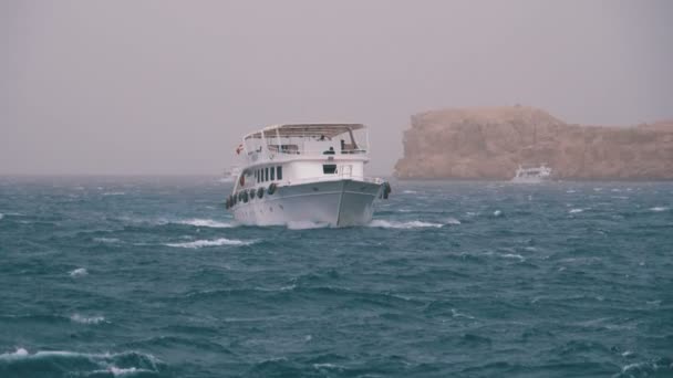 Fritidsbåt med turister seglar i storm havet på bakgrund av stenar. Egypten — Stockvideo