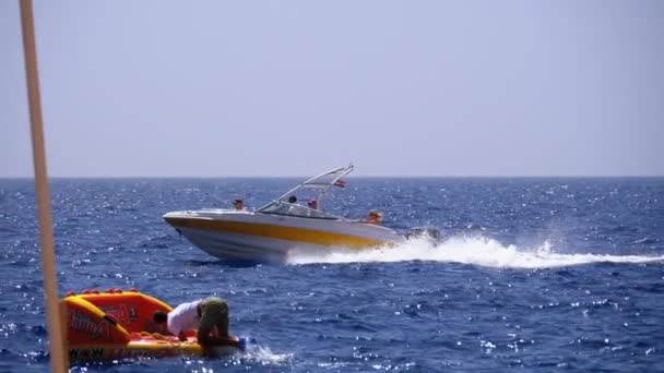 Barco a motor con la gente navega a lo largo de las olas en el mar rojo. Moción lenta — Vídeos de Stock