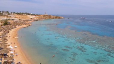 Reef'teki Luxury Sea Hotel'de Şemsiye, Şezlong ve Palmiyelerle Mercan Plajı'nın panoramik manzarası. Mısır.
