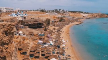 Reef'teki Luxury Sea Hotel'de Şemsiye, Şezlong ve Palmiyelerle Mercan Plajı'nın panoramik manzarası. Mısır.
