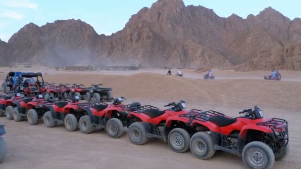 Η ομάδα των Red Quad ποδήλατα στέκεται σε ένα πάρκινγκ στην έρημο με φόντο τα βουνά. Οδήγηση ATVs — Αρχείο Βίντεο