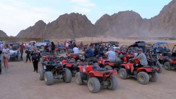 クワッドバイクのグループは、山を背景に砂漠の駐車場に立っています. — ストック動画
