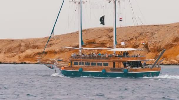 Schöne Touristenjacht segelt in der stürmischen See vor dem Hintergrund von Felsen. Ägypten — Stockvideo