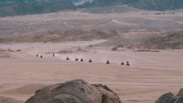 Grupa na quadach przejażdżki rowerem po pustyni w Egipcie na tle gór. Jazdy ATVs. — Wideo stockowe