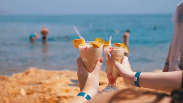 Два экзотических коктейля в руках девочек на фоне моря и пляжа в Египте . — стоковое видео