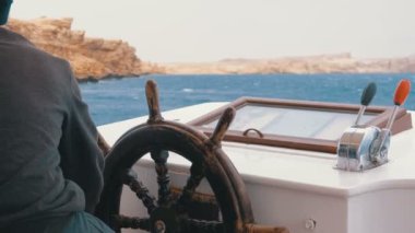 Bir zevk teknesinin direksiyonunda kaptan. Kaptan deniz yatı kontrol eder