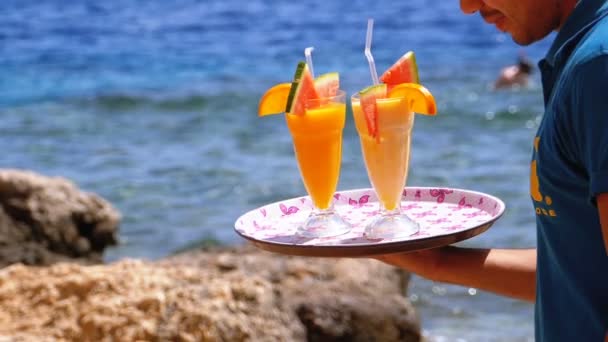 Exotische Cocktails in einem Glas mit einem Strohhalm auf einem Tablett auf dem Hintergrund des Meeres. Ägypten. — Stockvideo