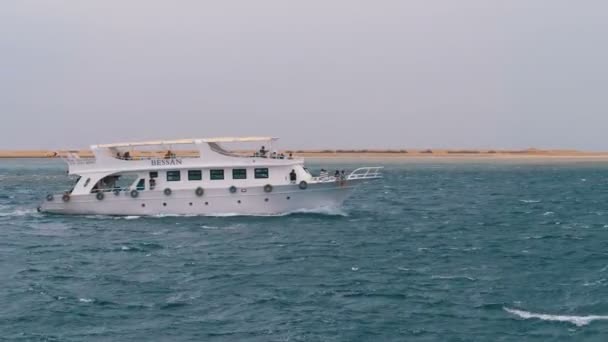 Ausflugsboot mit Touristen segelt in der stürmischen See vor dem Hintergrund von Felsen. Ägypten — Stockvideo