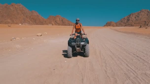 クワッドバイクの女の子は、山の背景にエジプトの砂漠を介して乗る — ストック動画
