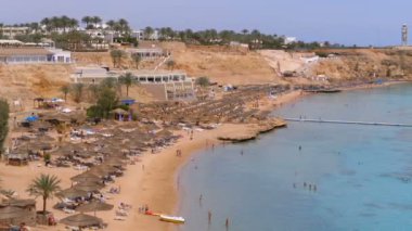 Reef'teki Luxury Sea Hotel'de Şemsiye, Şezlong ve Palmiyelerle Mercan Plajı'nın panoramik manzarası. Mısır.