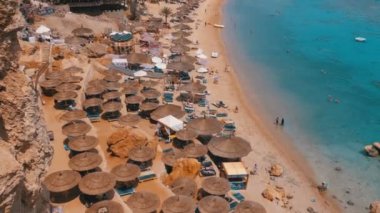 Reef'teki Luxury Sea Hotel'de Şemsiye, Şezlong ve Palmiyelerle Mercan Plajı'nın panoramik manzarası. Mısır.