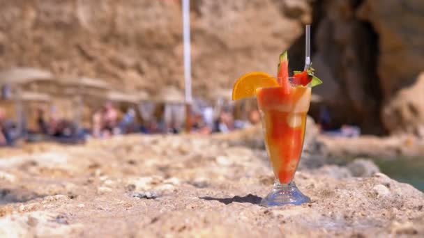 Τροπικό φρέσκο χυμό σε ένα ποτήρι με άχυρο στην παραλία της Αιγύπτου στέκεται πάνω σε ένα βράχο δίπλα στη θάλασσα — Αρχείο Βίντεο