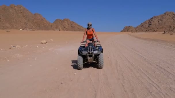 Mädchen auf einem Quad fährt durch die Wüste Ägyptens vor dem Hintergrund der Berge — Stockvideo