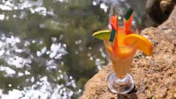 Tropische frisse cocktail in een glas met stro op het strand van Egypte staat op een rots op de achtergrond van de rode zee — Stockvideo