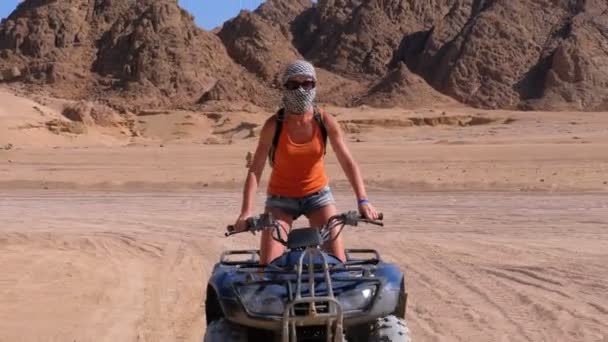 Сексуальная девушка на квадроцикле едет через пустыню Египта на фоне гор — стоковое видео