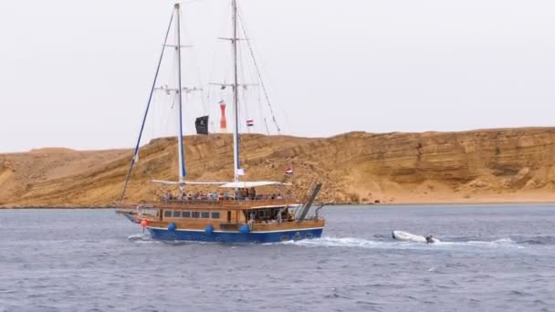 Hermoso yate de madera con los turistas está navegando en el mar tormentoso en el fondo de Rocas. Egipto — Vídeos de Stock