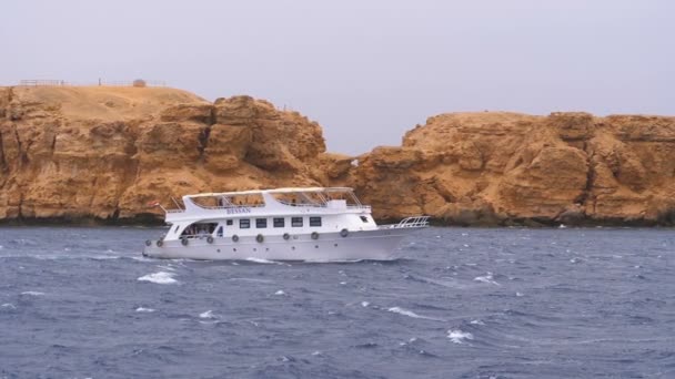 Barco de placer con los turistas está navegando en el mar de tormenta en el fondo de rocas. Egipto — Vídeos de Stock