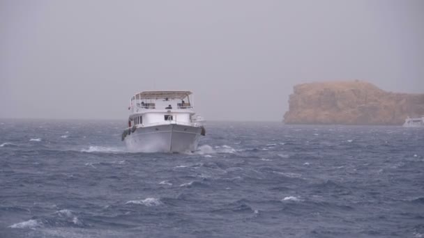 Barco de placer con los turistas está navegando en el mar de tormenta en el fondo de rocas. Egipto — Vídeo de stock