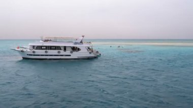 Beyaz kumlu ada yakınındaki turistik yatların arka planında şnorkelli yüzme ve tüplü dalış. Mısır