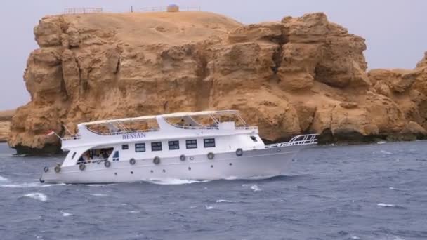 Piacere barca con le vele turistiche nel mare in tempesta sullo sfondo di rocce. Egitto — Video Stock