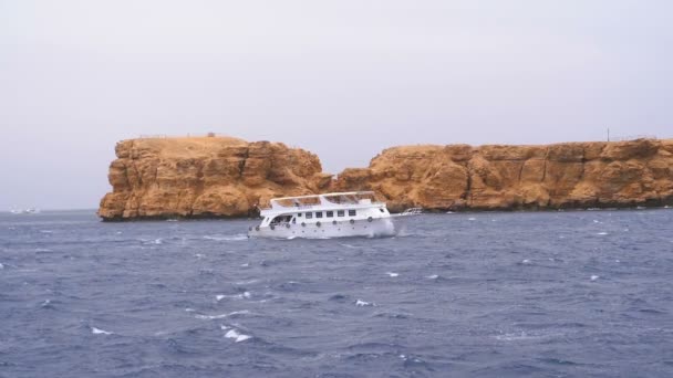 Plezierboot met toeristen is zeilen in de Storm Zee op de achtergrond van rotsen. Egypte — Stockvideo