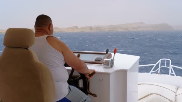 Tlustý kapitán ovládá turistickou jachtu v mořské bouři. Volant rekreační lodě. — Stock video
