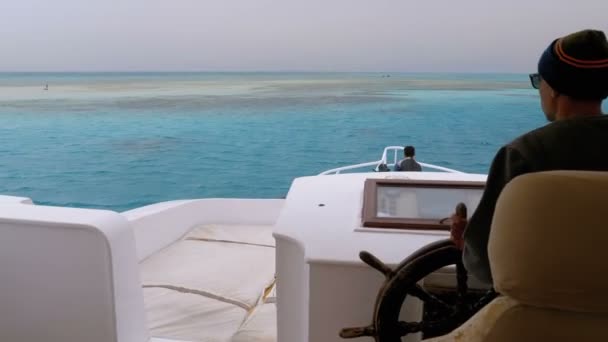 Der Kapitän steuert die Touristenjacht auf der weißen Sandinsel im Meer in der Nähe des Riffs — Stockvideo