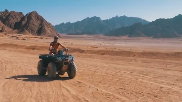 Сексуальная девушка на квадроцикле едет через пустыню Египта на фоне гор — стоковое видео