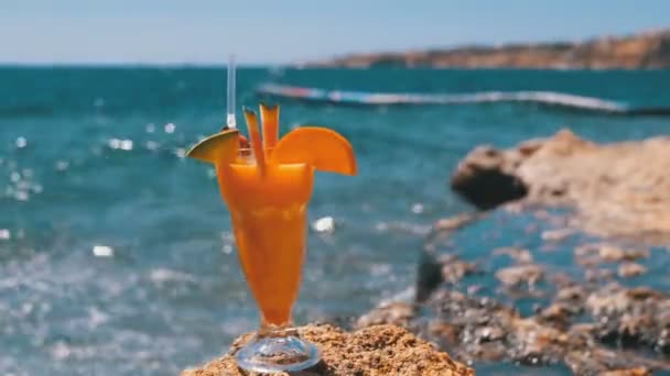 Tropisk fräsch cocktail i ett glas med halm på stranden i Egypten står på en klippa på bakgrund av Röda havet — Stockvideo