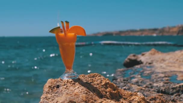 Tropisk fräsch cocktail i ett glas med halm på stranden i Egypten står på en klippa på bakgrund av Röda havet — Stockvideo