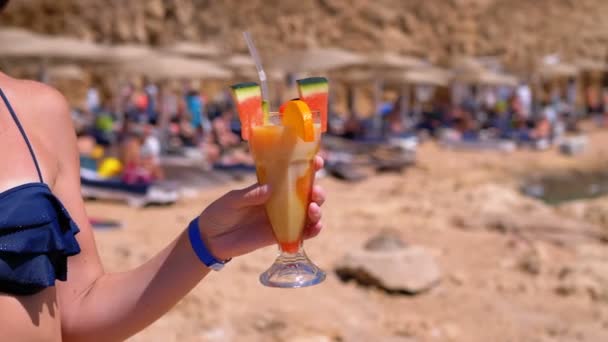 Молодая девушка в купальнике с экзотическим соком в руке на пляже в Египте — стоковое видео