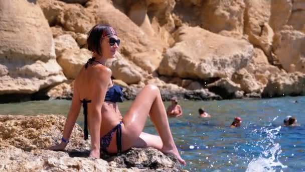 Sexy chica sentada en el acantilado en la playa rocosa de Egipto por el Mar Rojo — Vídeos de Stock