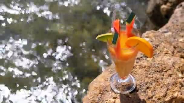 Tropisk fräsch cocktail i ett glas med halm på stranden i Egypten står på en klippa på bakgrund av Röda havet — Stockvideo