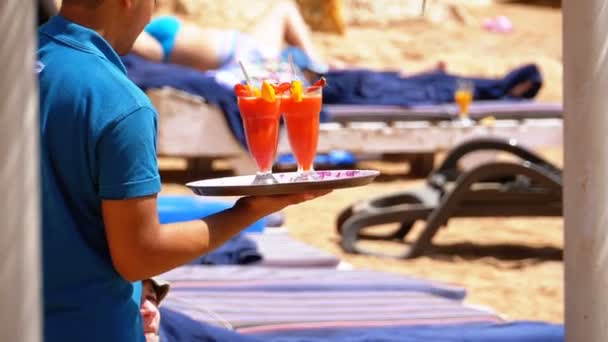 Garçom servindo bebidas na praia, Egito. Garçom segurando uma bandeja com sucos tropicais — Vídeo de Stock