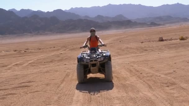 sexy Mädchen auf einem Quad fährt durch die Wüste Ägyptens vor dem Hintergrund der Berge. Zeitlupe