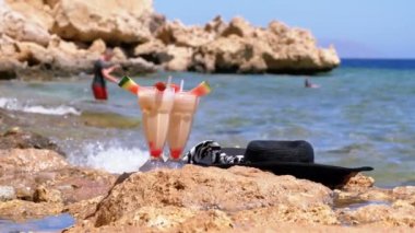 Mısır plajında Straw ile bir cam tropikal taze suyu deniz kenarında bir kaya duruyor. Yavaş hareket