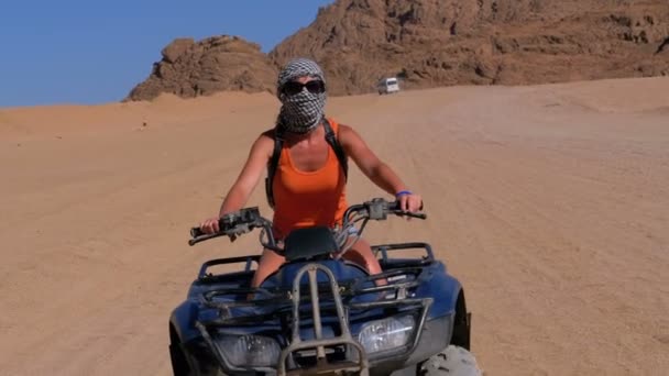 Девушка на квадроцикле едет через пустыню Египта на фоне гор. Slow Motion — стоковое видео