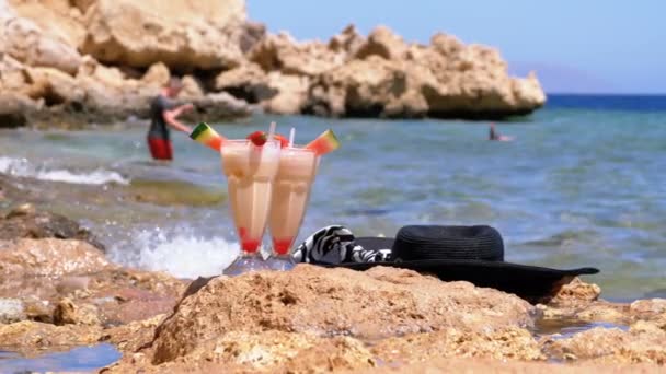 Zumo fresco tropical en un vaso con paja en la playa de Egipto está parado en una roca junto al mar. Moción lenta — Vídeos de Stock