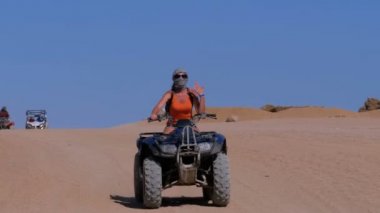 Dört bisiklet üzerinde kız dağlar arka planda Mısır çöl üzerinden rides. Yavaş hareket