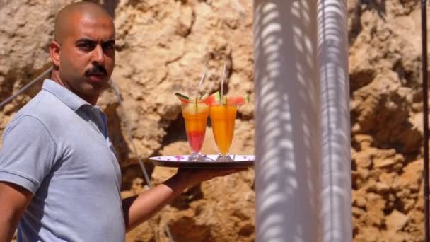 Camarero sirviendo bebidas en la playa, Egipto. Camarero sosteniendo una bandeja con jugos tropicales — Vídeos de Stock