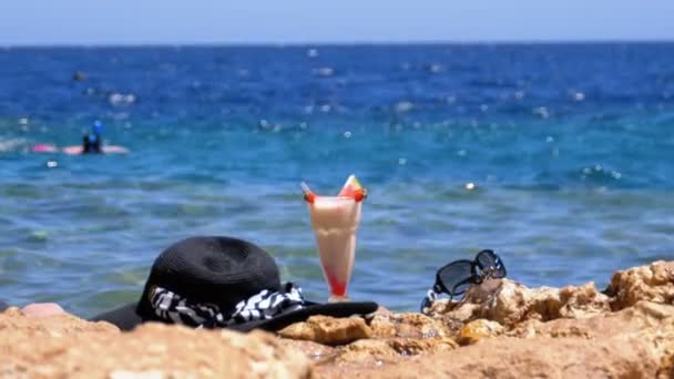 이집트 해변의 열대 신선한 주스, 모자, 안경은 바위 에 바다 — 비디오
