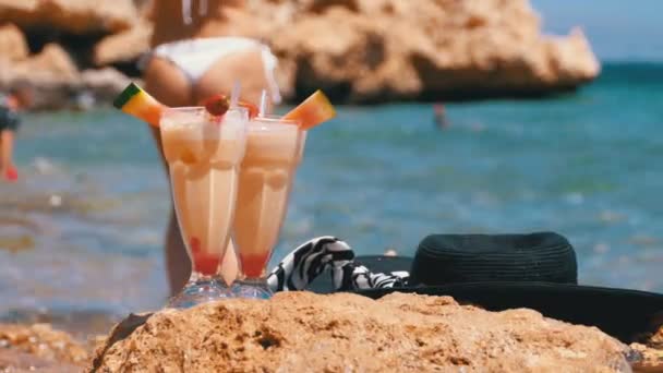 Succo di frutta fresca tropicale, cappello e bicchieri sulla spiaggia d'Egitto sta su una roccia vicino al Mar Rosso — Video Stock