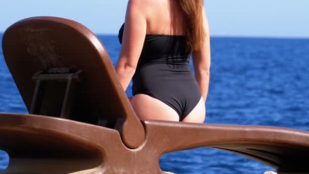 A mulher "sexy" em um Swimsuit está sentando-se em sunbed em uma praia de encontro ao mar vermelho em Egipto. — Vídeo de Stock