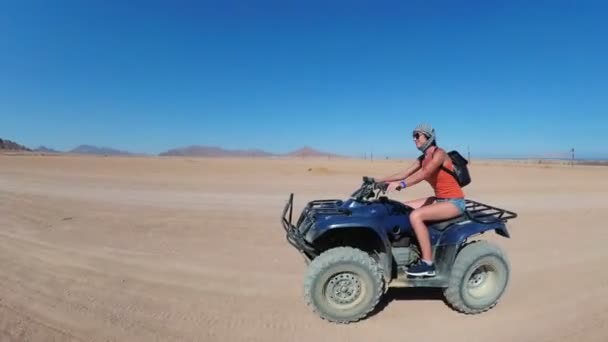 Sexy Girl está montando una bicicleta cuádruple en el desierto de Egipto. Vista dinámica en movimiento . — Vídeos de Stock