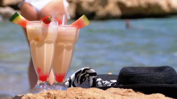 Zumo fresco tropical, sombrero y vasos en la playa de Egipto se encuentra en una roca junto al mar Rojo — Vídeo de stock