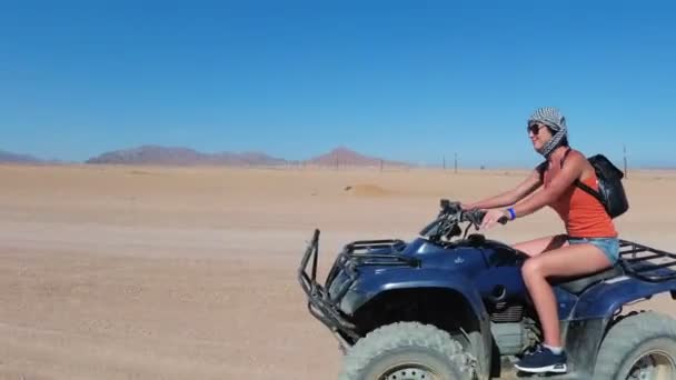 섹시한 여자는 이집트의 사막에서 쿼드 바이크를 타고있다. 움직이는 동적 뷰. — 비디오